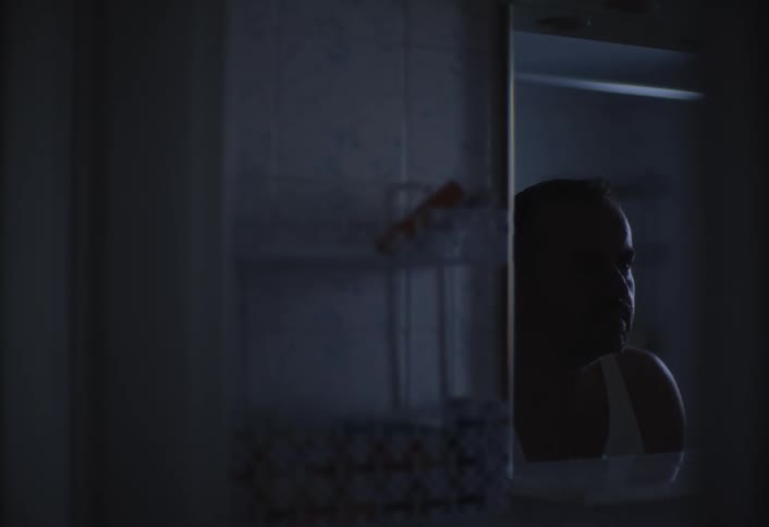 Man in front of bathroom mirror washing his face