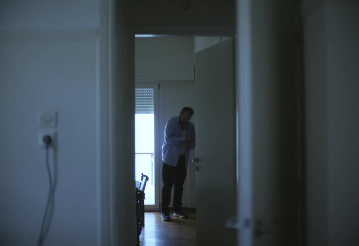 A man stands at his closet buttoning a formal shirt as he gets dressed