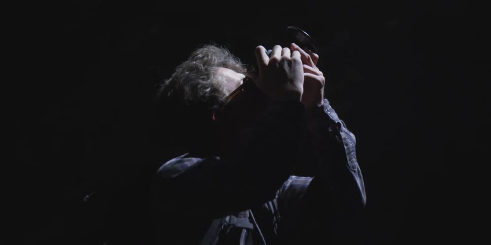Male photographer standing under a light in a dark area takes a picture