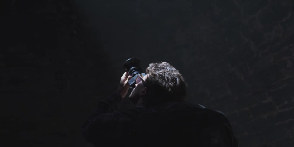 Man pointing a professional camera upwards inside a cave