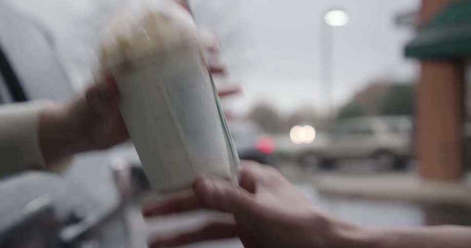 A person gets their drink at a starbucks drive through
