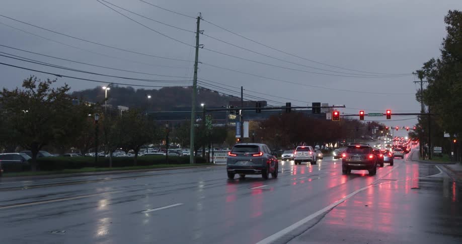 A dark suv is seen in motion with a faint view of the interior through tinted windows on a rainy day