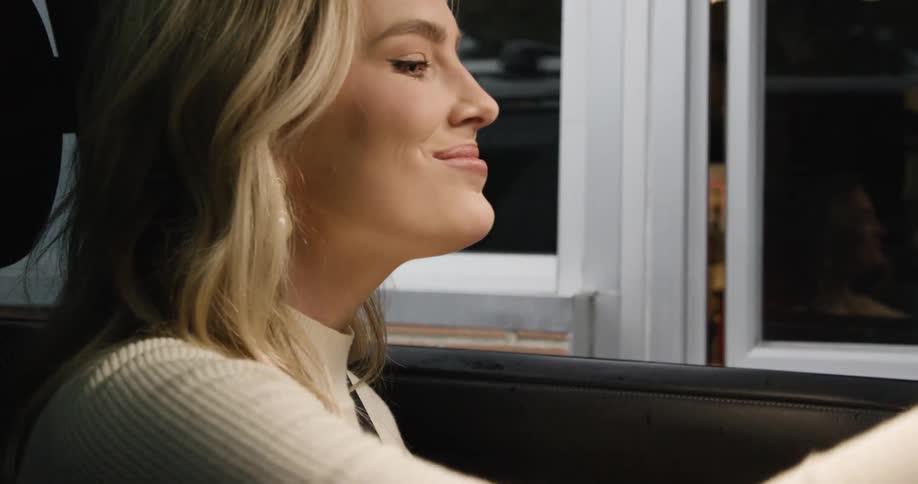 A woman in a car receives a drink from a drivethru employee through a service window