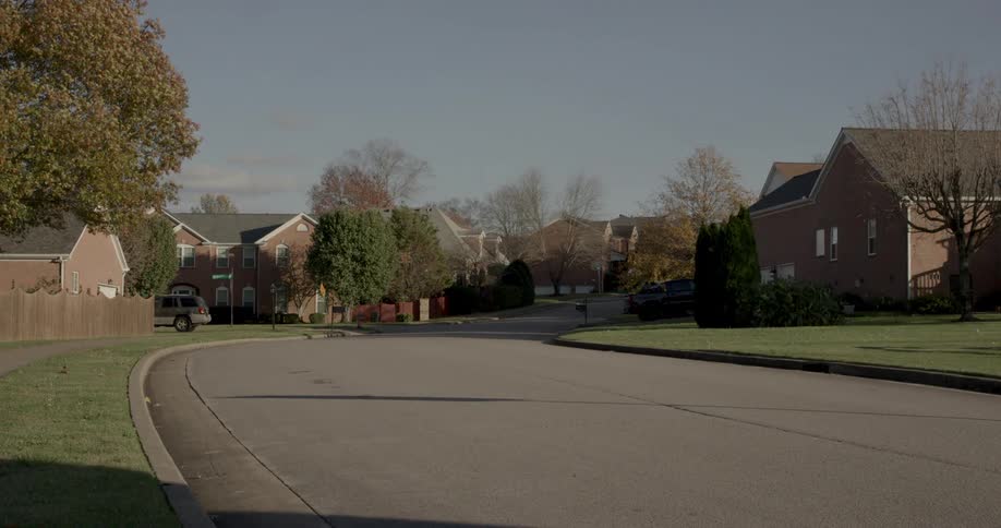 A delivery truck drives through a quiet suburban neighborhood in daylight