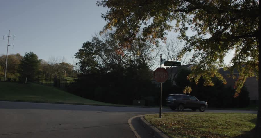A black suv drives through a quiet suburban neighborhood on a clear day