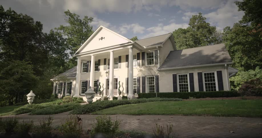 Luxury home with columns and black shutters in a residential neighborhood
