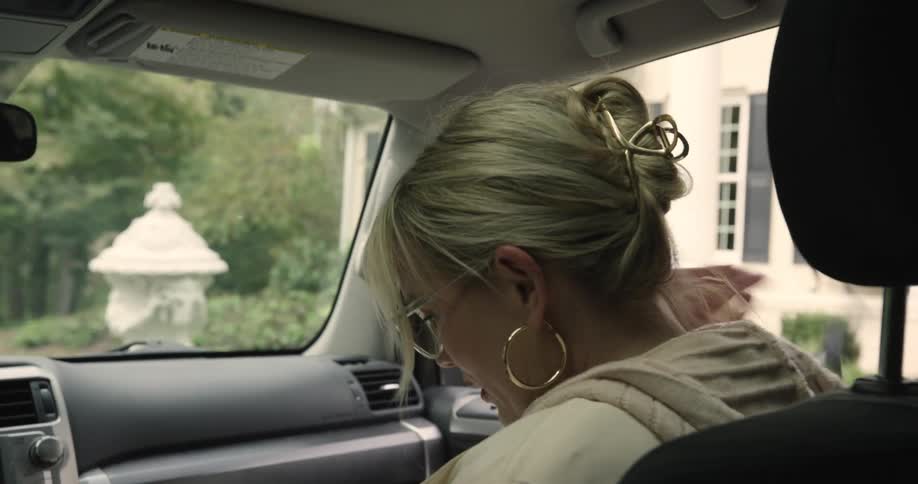 Woman taking off her front seat belt and getting out of the car