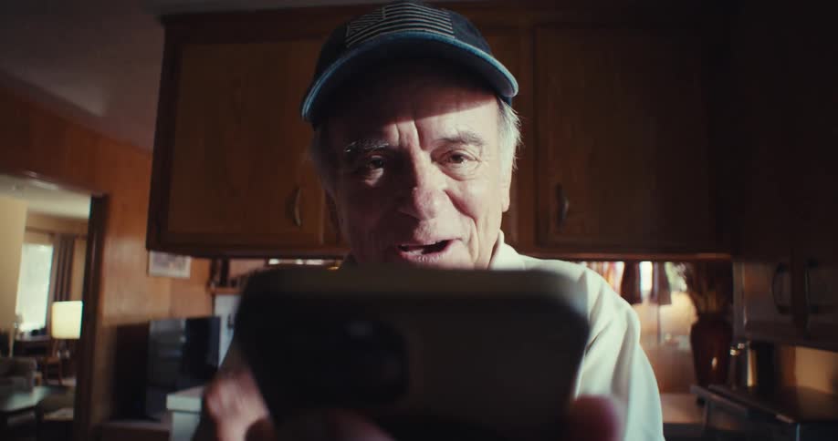Point of view happy older man greeting hello while facetiming on his cell phone