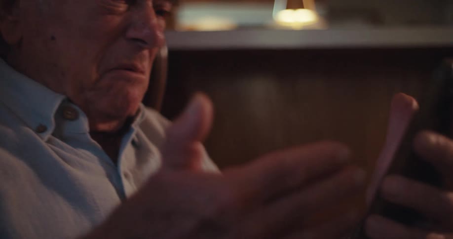 Elderly man sitting interacting with a smartphone