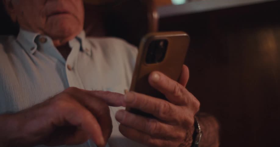 Elderly man sitting in an armchair interacting with a smartphone