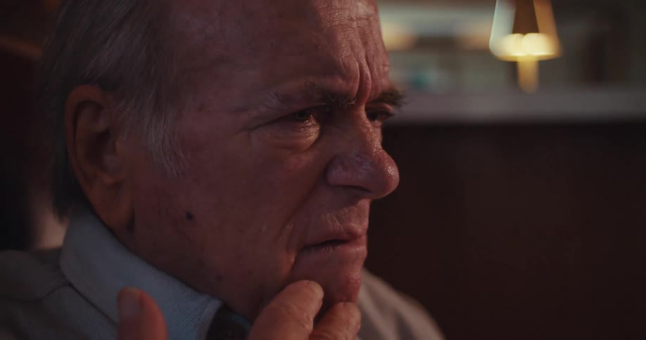 Elderly man sitting at homeis upset by what he is seeing on his smartphone