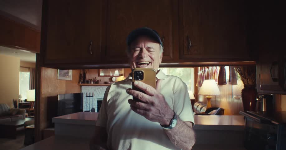 Elderly man laughs while watching something funny on his phone