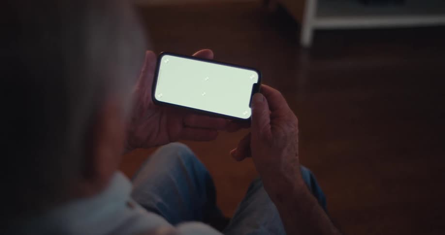 Elderly man sitting and turning a smartphone sideways
