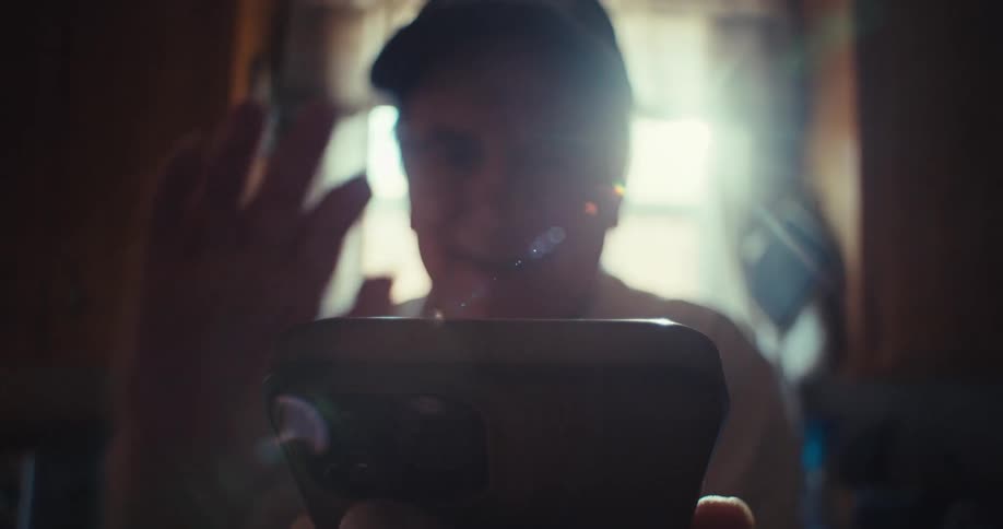 An elderly man smiles warmly while video calling in a sunlit kitchen