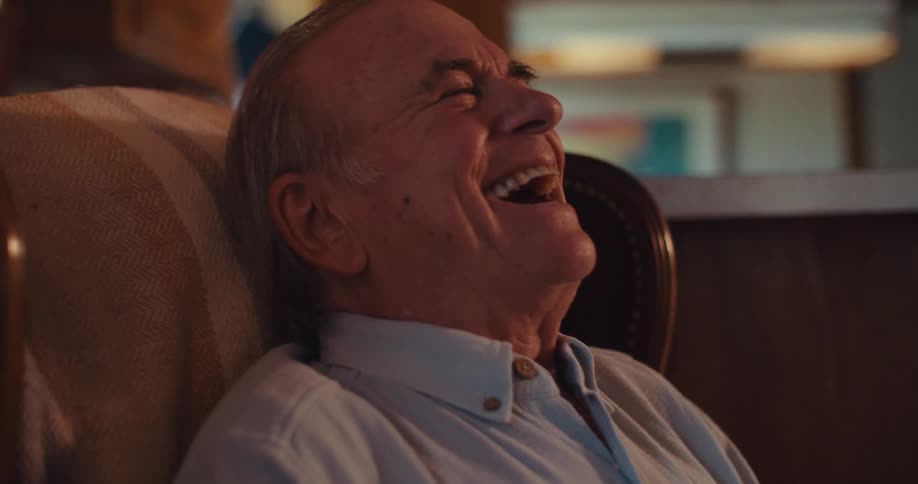 The man laughs hard when looking at his phone