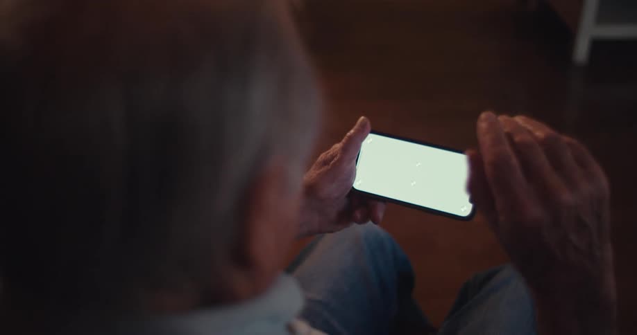 Elderly man waving his hand towards a smartphone