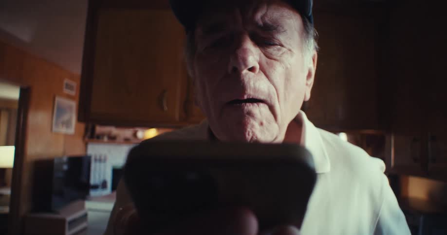 Elderly man with happy expression holding and interacting with a smartphone