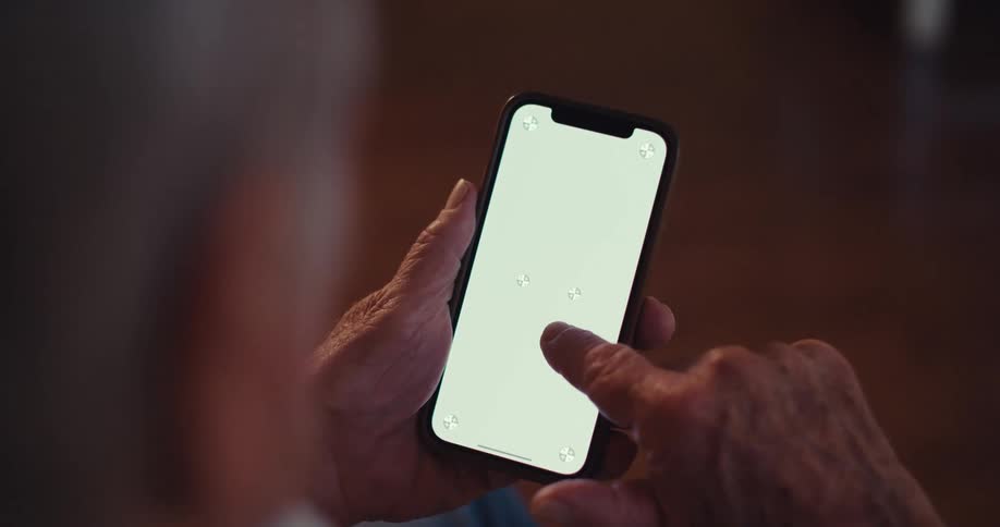 Elderly man in an indoor space interacting with a smartphone