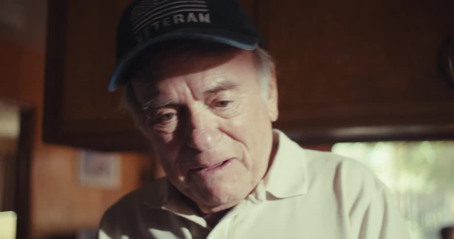 An older man waves and laughs while enjoying a video call