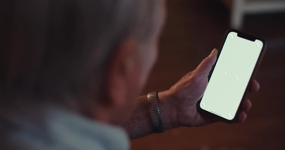 Elderly man sitting interacting with a smartphone