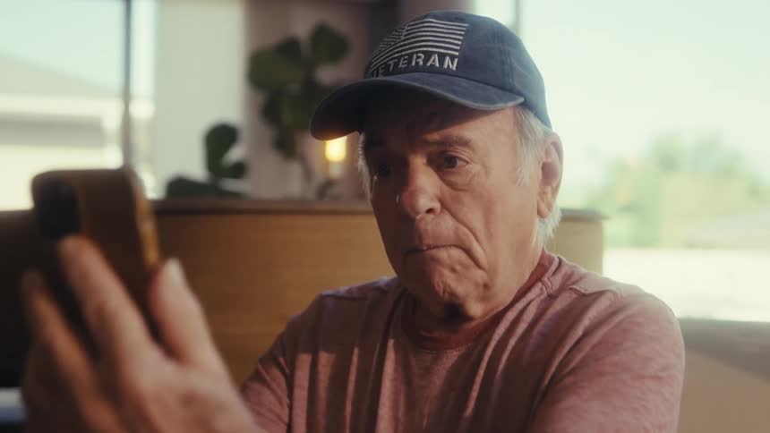 Elderly man sitting with a smartphone towards his face