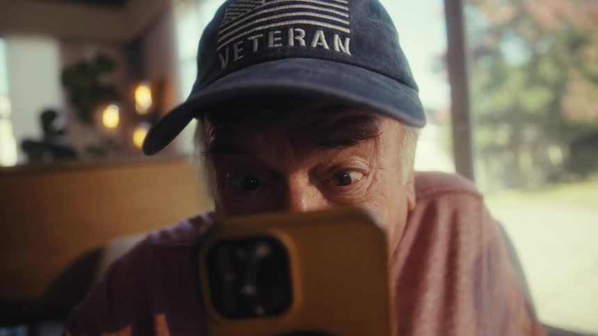 Happy and concentrated elderly man watching on a smartphone