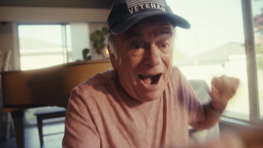 Elderly man jumps up excitedly while watching into his smartphone
