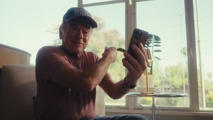 Elderly man talking on a video call while sitting indoors