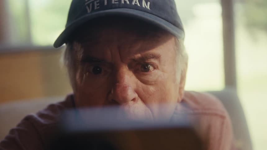 Elderly man wearing a cap vibrating extremely happily in front of a smartphone