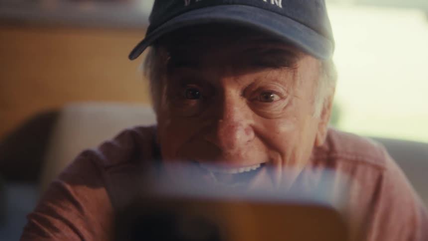 Elderly man vibrating happily in front of a smartphone