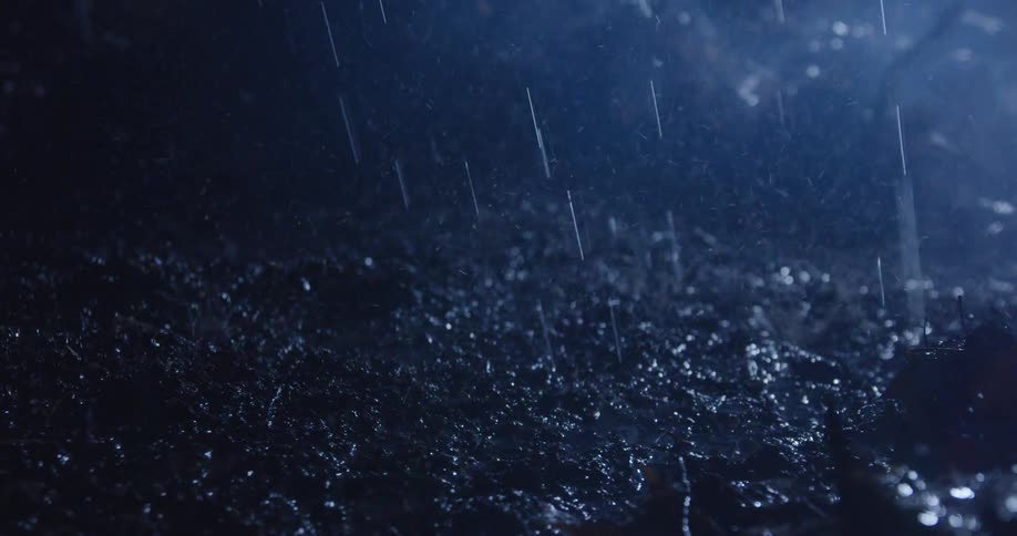 The video shows a dark blurred shot of rain falling with visible streaks of water against a dark background the water splashes on an unseen surface creating a dynamic and immersive effect of a heavy downpour
