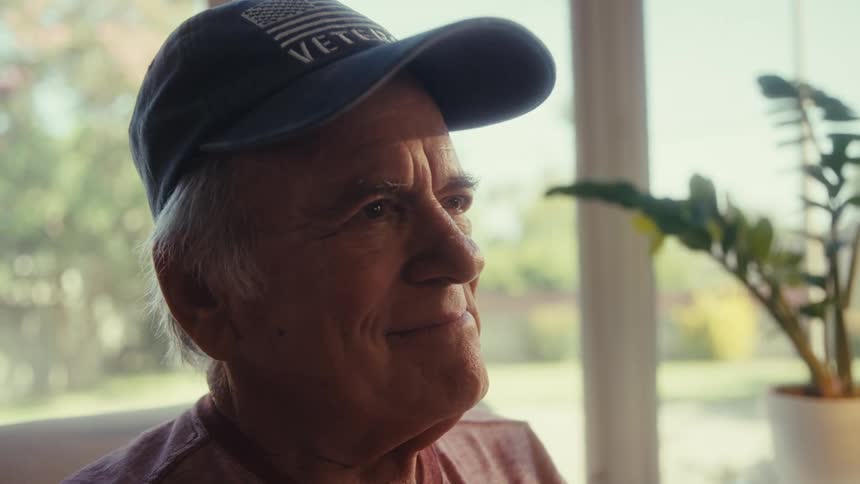 Elderly man wearing a cap sitting with a happy expression