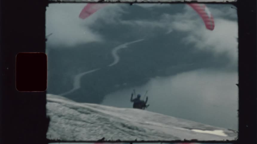 Friends film as one paraglides over scenic mountains