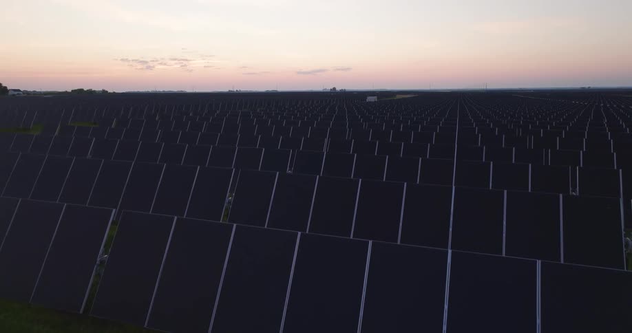 Low skim over a large installation of solar panels at dawn