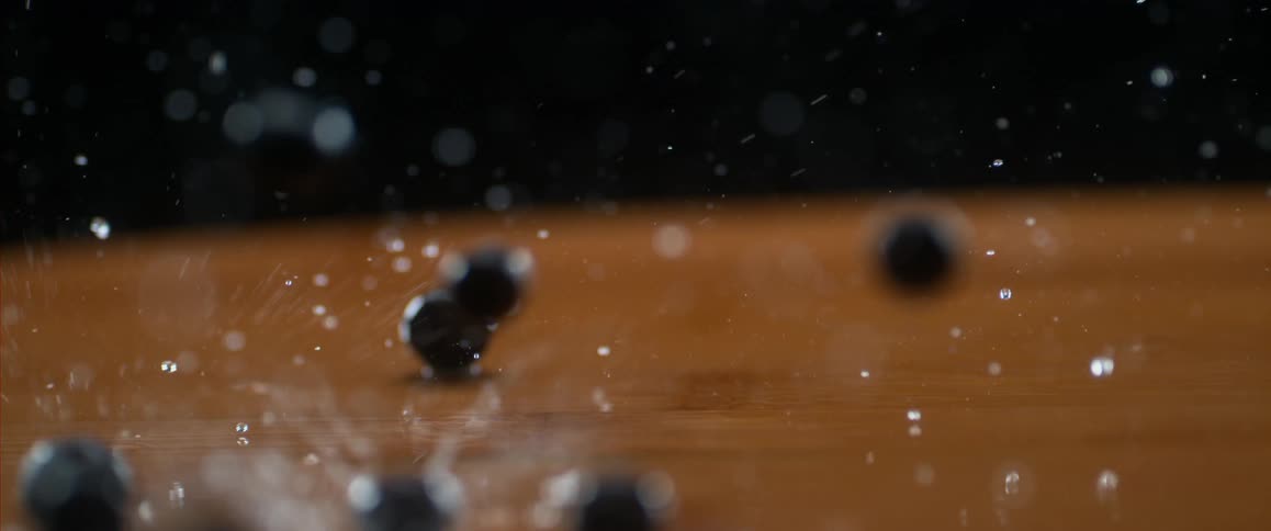 Blueberries and water drop onto wooden surface