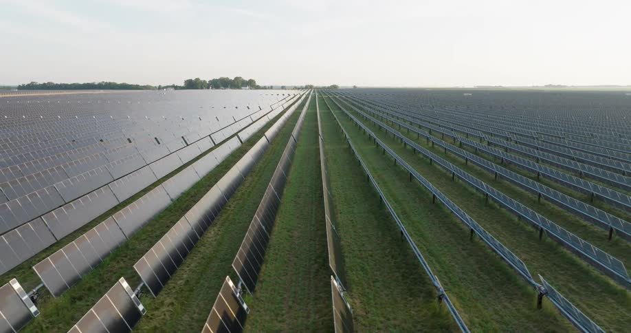 Long rows of gleaming panels stretch to the horizon at an enormous solar farm