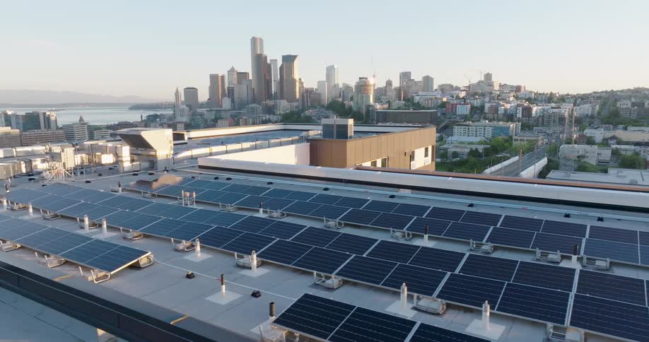 Solar panels cover the roof of a large building in a coastal city