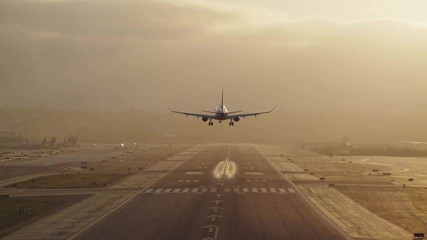 A large plane landing on a huge asphalt runway with white stripes