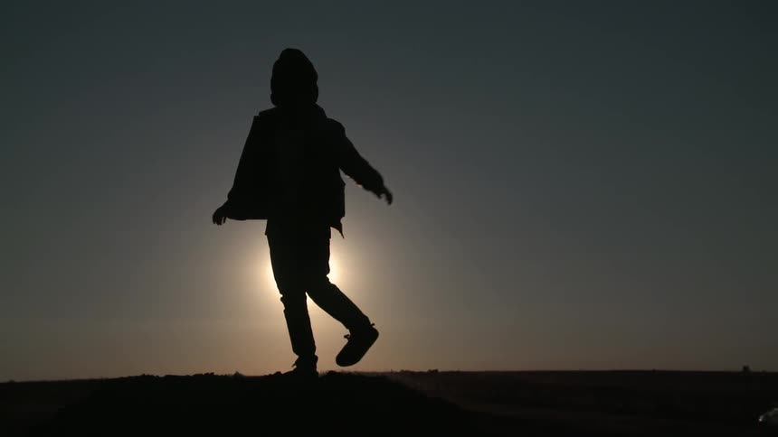 A boy is silhouetted by the bright sun