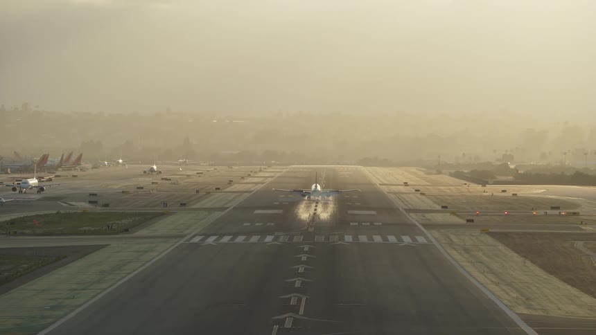 A commercial airplane approaches a runway for landing under overcast skies