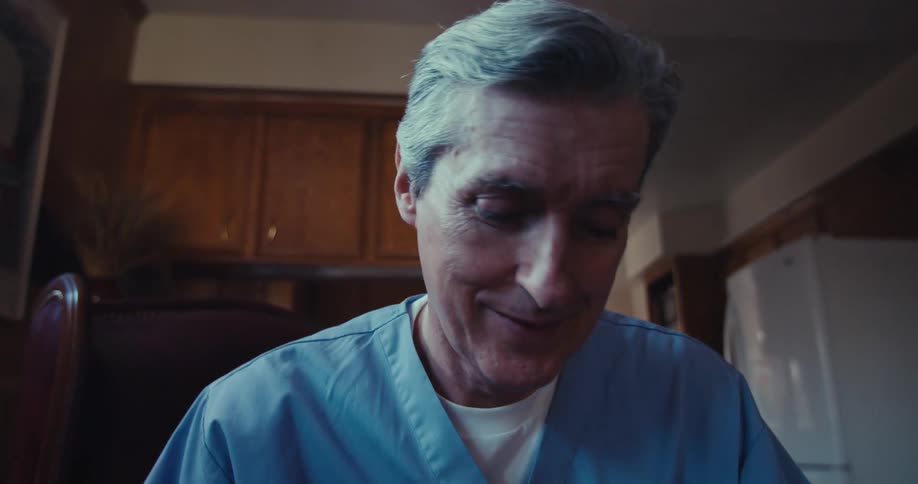 A doctor is seated writing on a file while talking to a patient