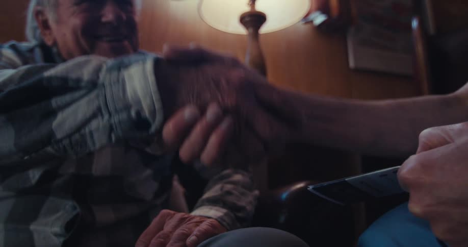 Person shaking hands with an elderly man with a happy expression