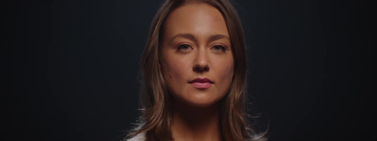 Light shines onto the face of a woman rotating in a dimly lit area