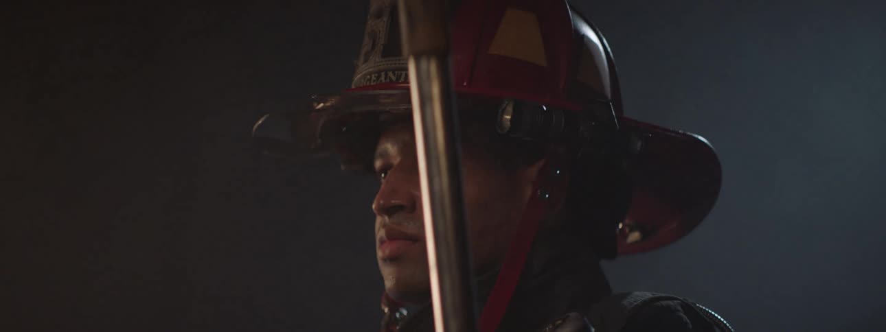 The firefighter is posing in the dark room