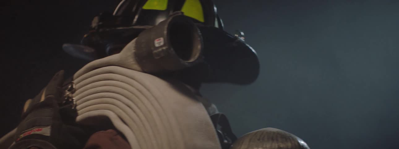 The fireman has a hose slung on his shoulder