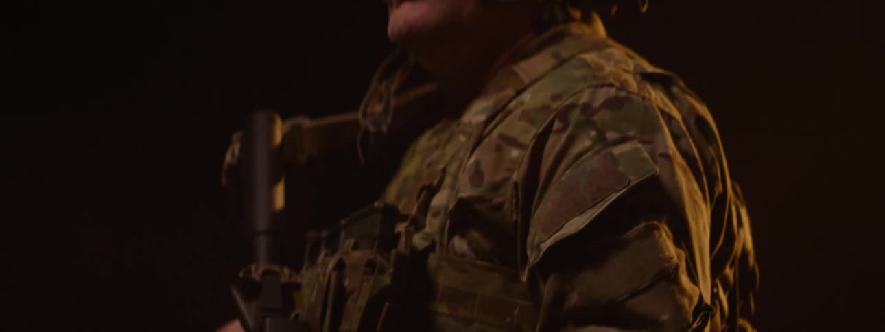 A military officer wearing a helmet and full uniform holding a weapon