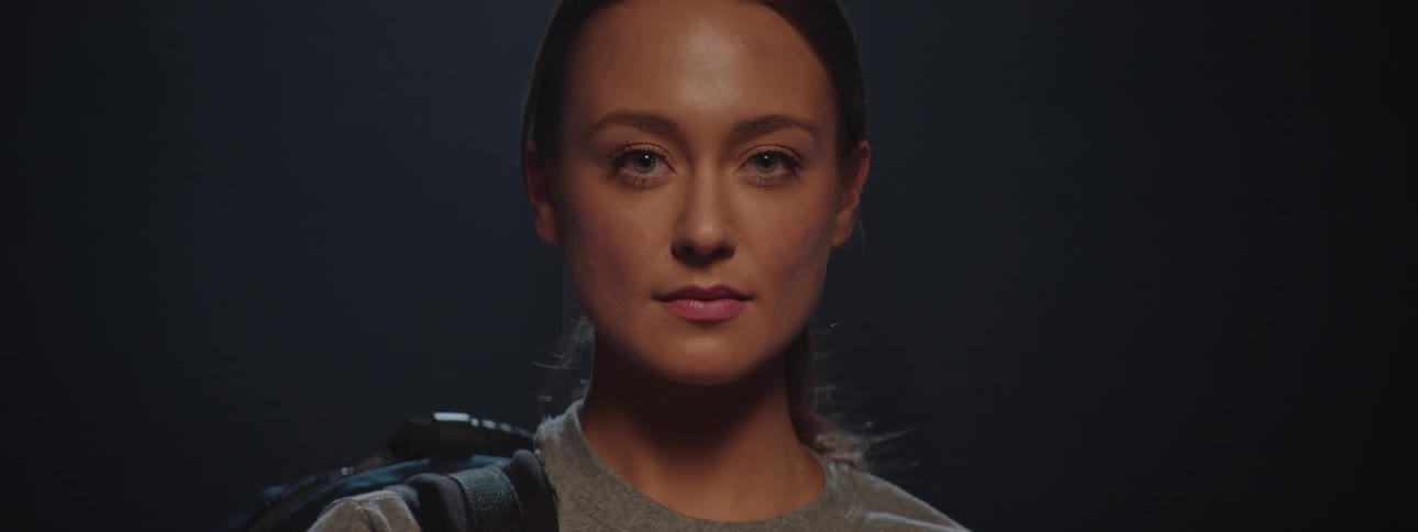 Woman with light eyes in a lowlight environment and with a backpack on her back