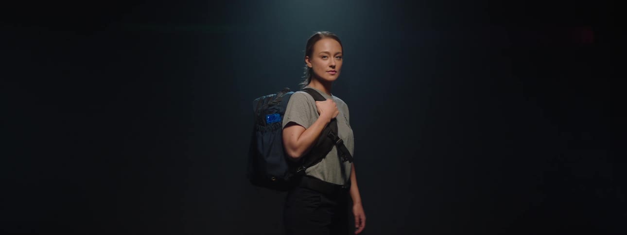 A model is holding a backpack in the foggy room
