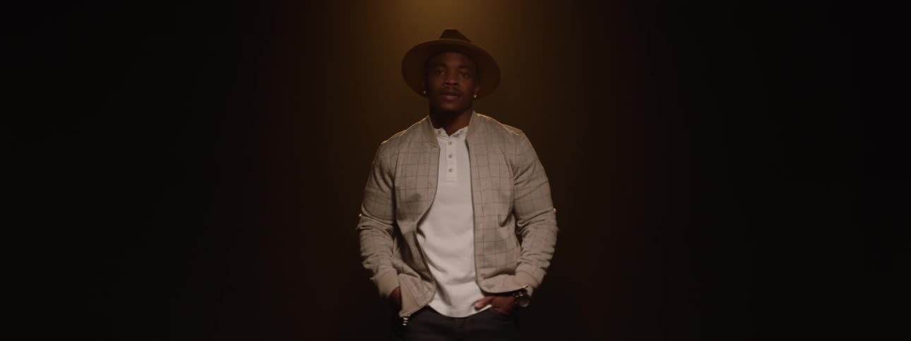 Man in hat and shirt in a lowlight indoor space