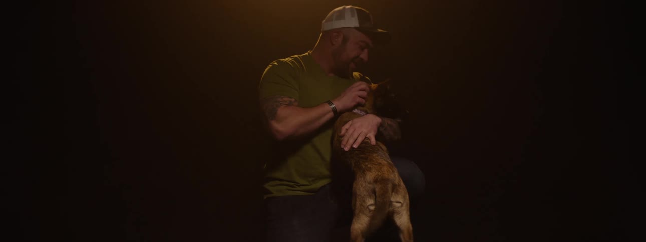 Man on his knees playing with a dog